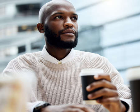 Coffee stirs all the ambitious thoughts. Shot of a young businessman looking thoughtful while...