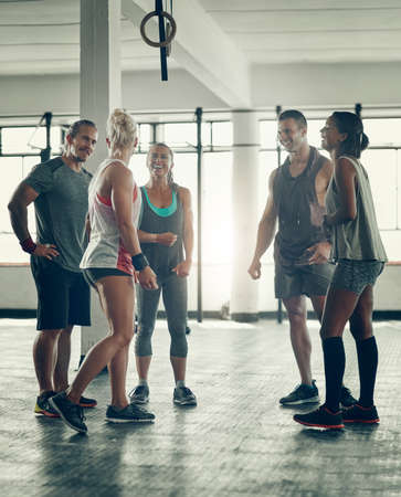 Supporting and challenging each other. Shot of a group of young people working out together at the gym.の写真素材