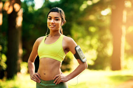 Working out can only make you happier. Shot of a sporty young woman outdoors.の写真素材