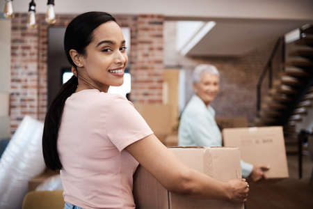 Brand new home, here we come. Shot of a young woman helping her elderly mother move house.の写真素材