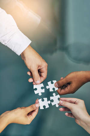 We fit together as a team. Shot of hands putting puzzle pieces together.