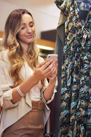 Sweet texts always make me smile. Shot of a young woman using her smartphone while shopping.