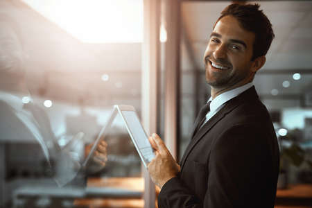 Im getting it all done the smart way. Portrait of a young businessman using a digital tablet in an office.の写真素材