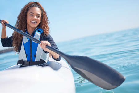 Paradise is just a paddle away. Portrait of a young woman kayaking at a lake.
