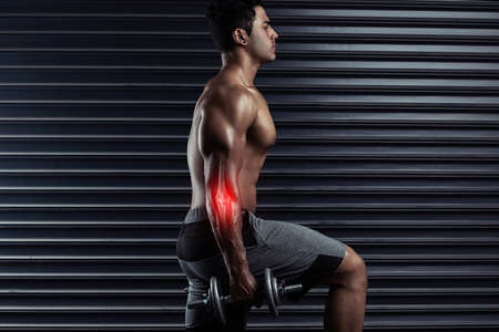 His joints are taking a beating. Cropped shot of an athletic young man working out with dumbbells.