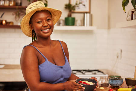 I dont quit when the bets are down. Portrait of a young beautiful woman wearing a sunhat while preparing breakfast at home in the kitchen.の写真素材