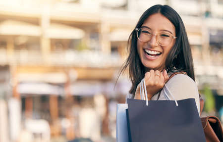 I got it all. Portrait of an attractive young woman walking alone outside while shopping in the city.の写真素材