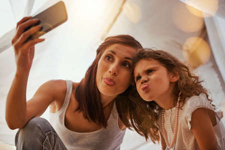Pull a funny face. Shot of a mother and daughter having fun and taking a photo together while...