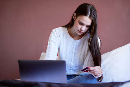 Paying off debts has never been more satisfying. Shot of a young woman shopping online using her...