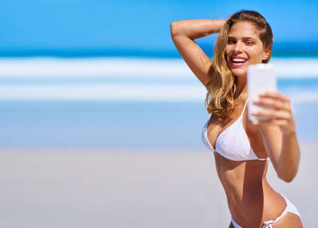 Celebrating summer with a sexy selfie. Shot of an attractive young woman enjoying a vacation at the...