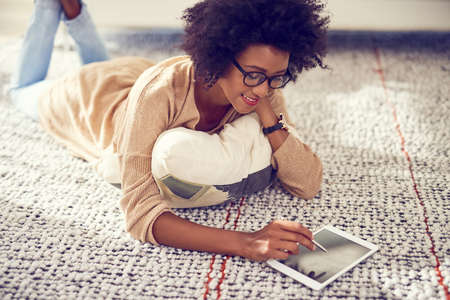 Keeping her screen scratch free with a stylus. Shot of a young woman using a digital tablet at home.