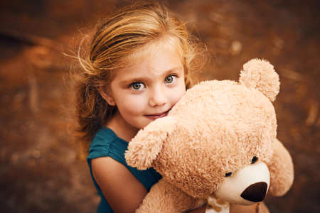 Teddy and I will never part. Shot of a happy little girl looking at the camera and holding her teddy...
