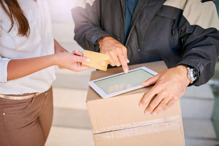 Paying by credit. Shot of a businesswoman using a credit card to pay for a delivery made by a...
