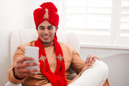 Big style for a big day. Shot of a young man using a smartphone on his wedding day.