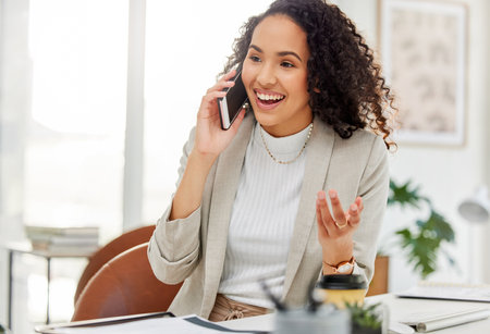 Delivering some exciting news to her client. Shot of a young businesswoman talking on a cellphone in an office.の写真素材