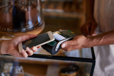 Gone are the days of carrying cash on you. Closeup shot of a customer paying using NFC technology in...