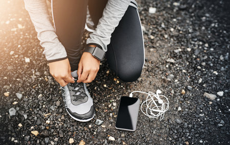 Tie those laces and get moving. Closeup shot of a sporty woman tying her shoelaces while exercising...