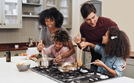 How does it taste Dad. Shot of a family of four cooking together in their kitchen at home.の写真素材