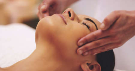 My mind is finally at ease. Shot of a beautiful young woman enjoying a head massage at a beauty spa.の写真素材