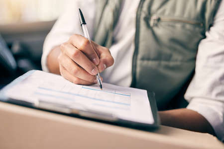 No one is more organised than a delivery man. Shot of a delivery man writing on a clipboard while...