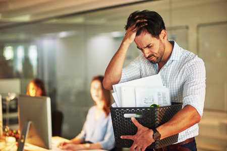He just got his marching orders. Shot of a stressed businessman holding his box of possessions after...