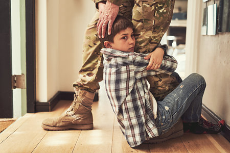 Dont leave me daddy. Shot of a young boy clinging to his fathers leg to stop him from going to the army.の写真素材