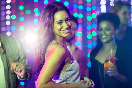 Heating up the dancefloor. Portrait of a beautiful young woman posing on the dancefloor in a nightclub.の写真素材