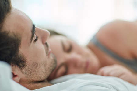 Having someone to share your life with is beautiful. Shot of a relaxed young couple sleeping in bed together at home.の写真素材