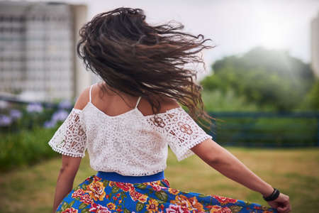 Nothing can contain her free spirit. Rearview shot of a young woman dancing in the city.