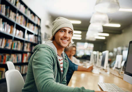 Studying is tough, but its rewarding. Cropped portrait of a young male university student studying in the library.の写真素材