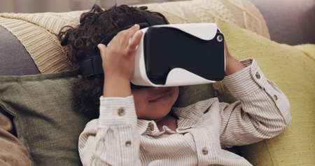 Glued to the screen. Shot of a little boy watching movies together through virtual reality headsets...