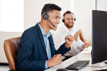 Wow, I cant believe my luck. Shot of a young call centre agent cheering while working in an office.