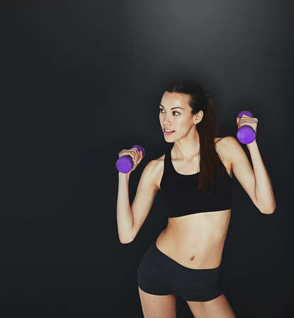 Stay dedicated. Shot of a young woman working out with dumbbells.