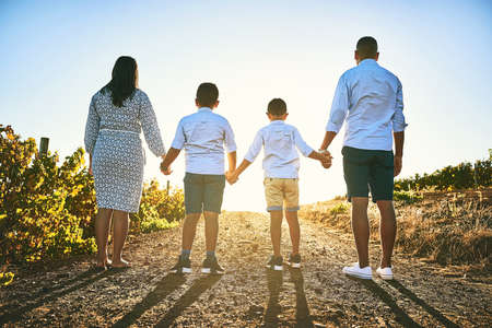 Families stand together forever, no matter what. Rearview shot of a family bonding together outdoors.の写真素材