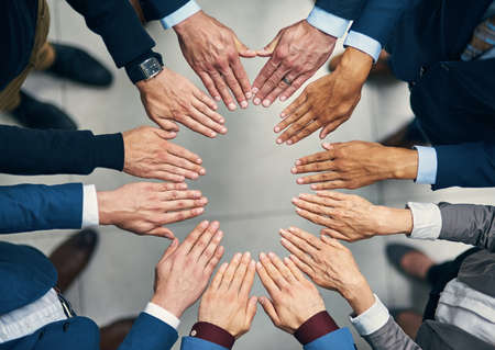 You cant get to success without having solidarity. High angle shot of a group of businesspeople joining their hands together in unity.の写真素材