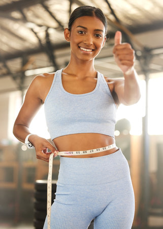 Not every loss is a failure. Portrait of a fit young woman measuring her waistline in a gym.の写真素材