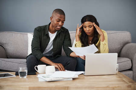 I hope we have enough saved up. Shot of a young couple going over bills together at home.の写真素材