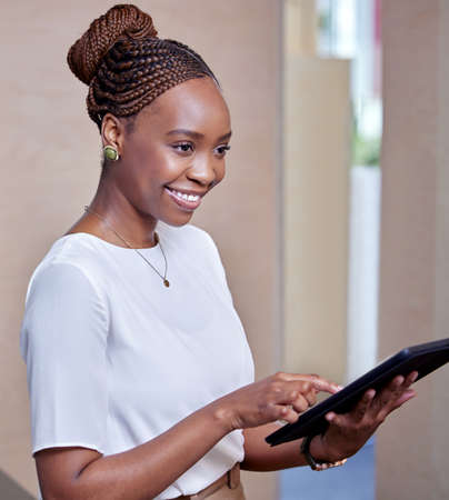 Theres always time to look things over twice. Shot of a young woman using a digital tablet in a...