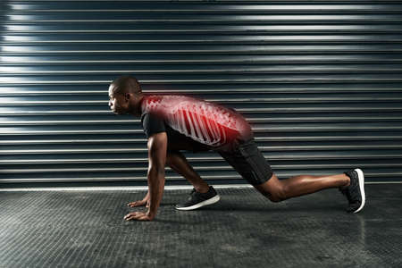 On his mark. Full length shot of an athletic young man ready on his mark in the studio.