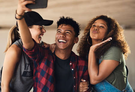Smile for the camera my friends. Portrait of a group of cheerful young friends posing for a self...
