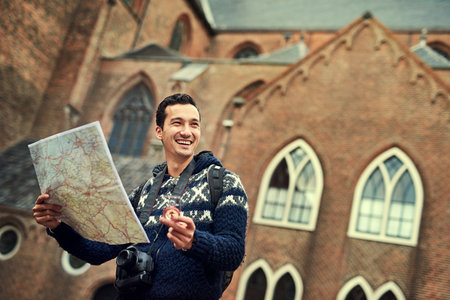 Finding his way. Cropped shot of a young man looking at a map while on vacation.