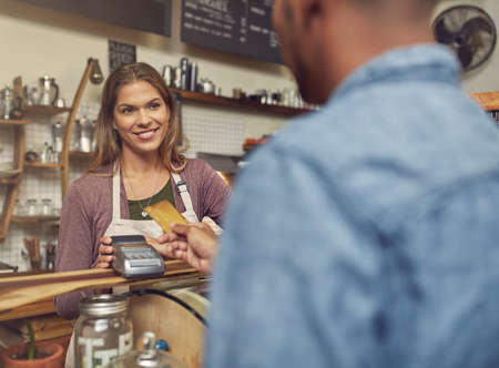 Yes, we do accept credit cards. Shot of a store assistant taking a credit card payment from her customer.の写真素材