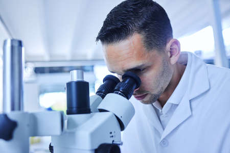 Seeing things the human eye cant. Cropped shot of a handsome young male scientist working with a microscope in his lab.の写真素材