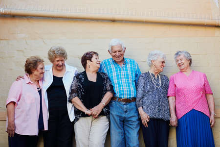 The older we get, the more we enjoy life. Shot of a group of seniors standing against a wall outside.の写真素材
