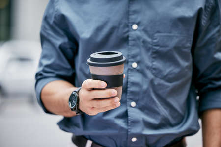 Have a break. Cropped shot of an unrecognizable businessman holding a takeaway coffee while standing...