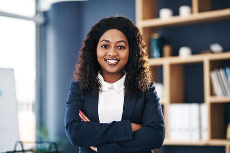 Never stop growing your career. Shot of a young confident businesswoman working in a modern office.の写真素材