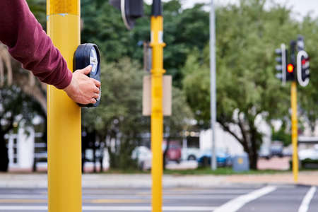 Waiting to walk. Shot of a mans hand pressing the crossing button at an intersection.