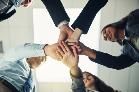 Come together and make it happen. Cropped shot of a group of businesspeople joining their hands in solidarity.の写真素材