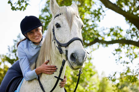 Feeling free on her horse. Shot of an attractive young woman standing with her horse in a forest.