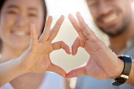 No hiding our love. Cropped shot of an affectionate young couple making a heart shape with their hands on the beach.の写真素材